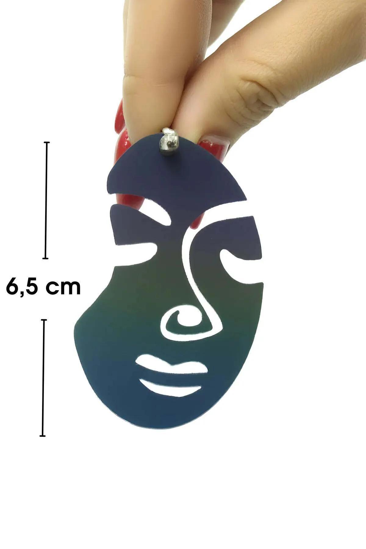 Close-up of white reflective polymer abstract face earring showing carved eye nose and lip cutout lines