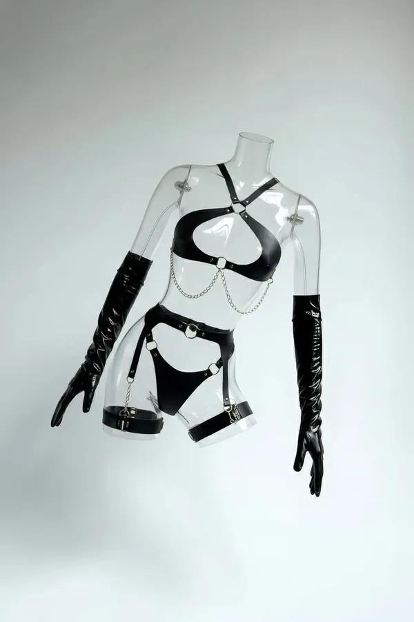 Faux leather harness set in black color featuring a heart shaped bra, draping silver chains, and garter straps.