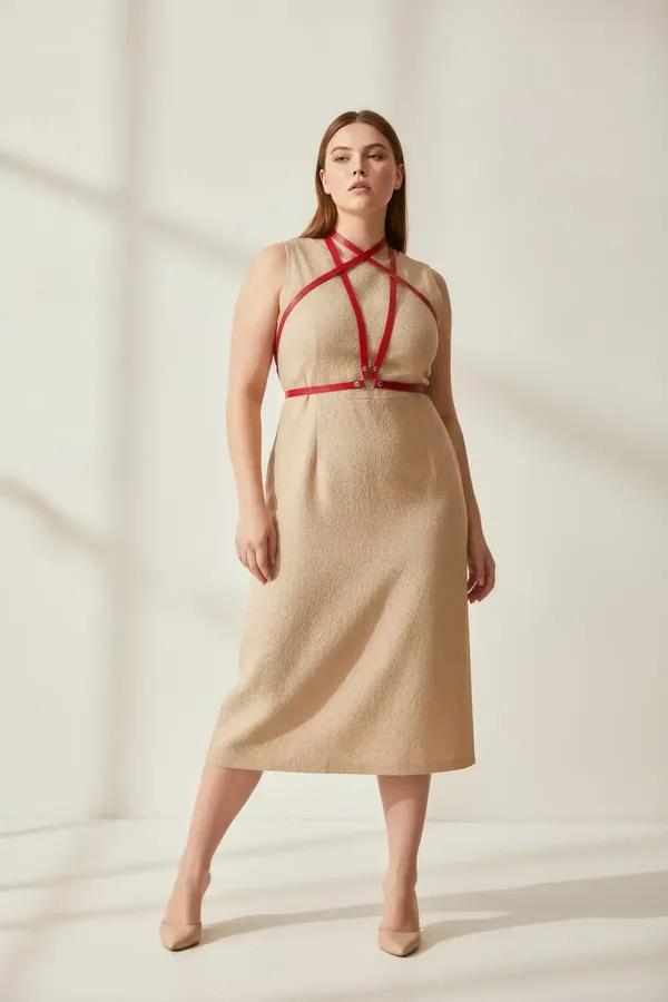 red faux leather overbust harness with waist belt and silver O-ring worn over a black dress