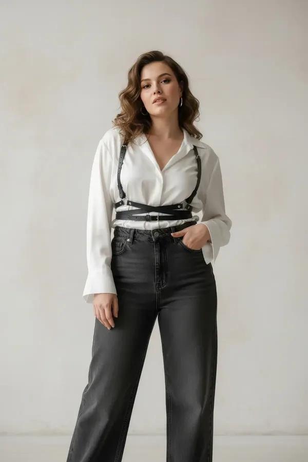 Black faux leather cross-strap underbust harness with criss-cross waist straps and silver buckles worn over white turtleneck