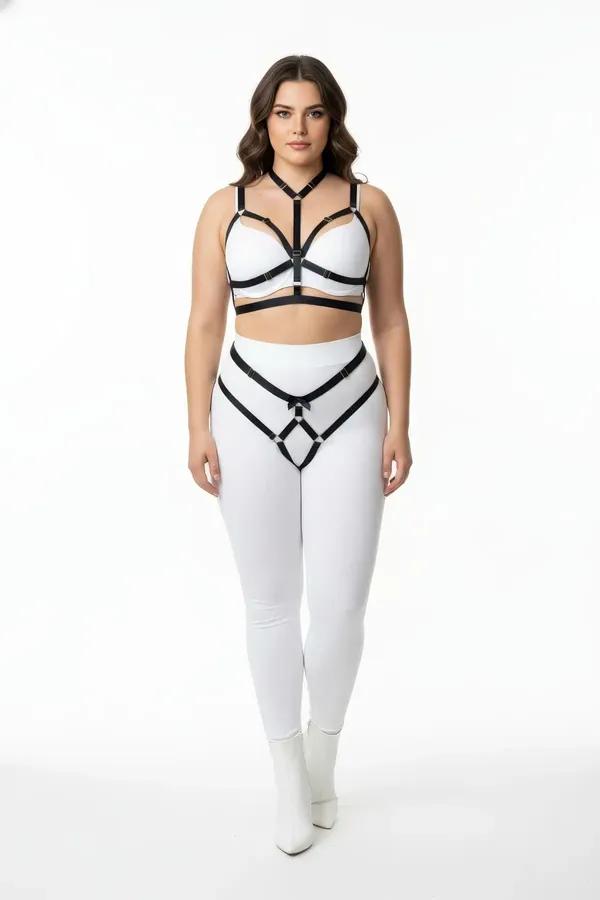 black vegan leather body harness and garter belt set with silver O-rings worn over white leggings, plus size model