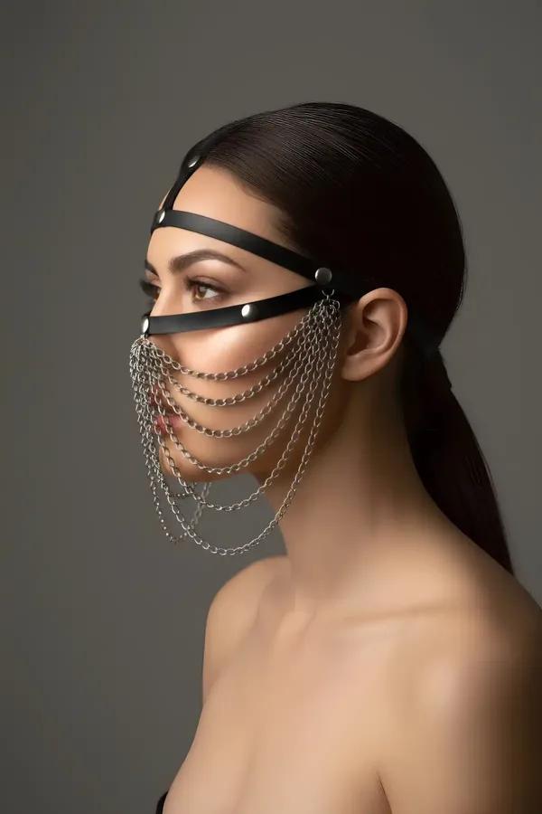 black faux leather face harness with seven draping silver chains and O-ring detail worn as a chain veil mask
