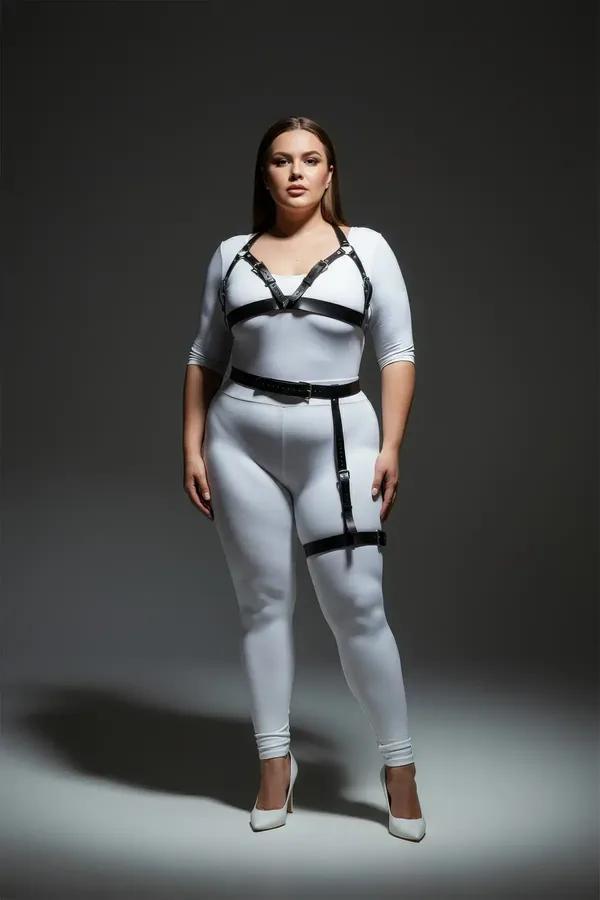 Black faux leather harness bra and thigh garter set with silver buckles worn over white outfit