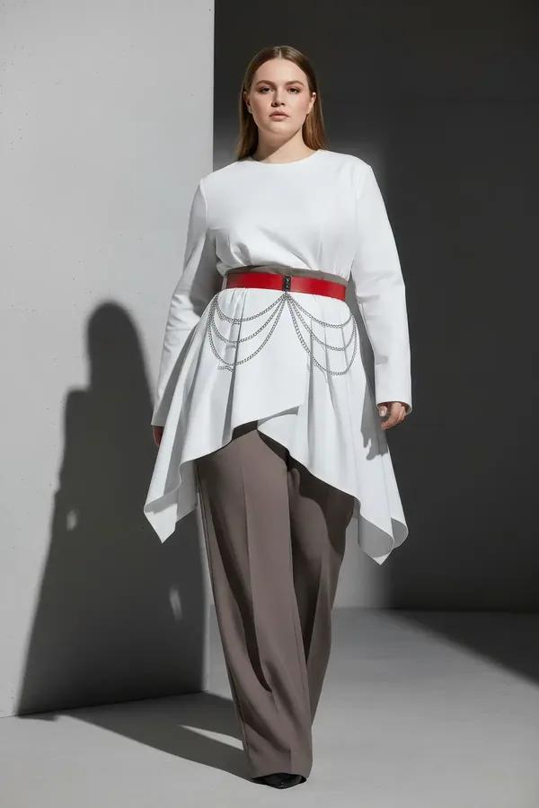 red faux leather wide waist belt with draped silver chains worn over white blouse and grey trousers