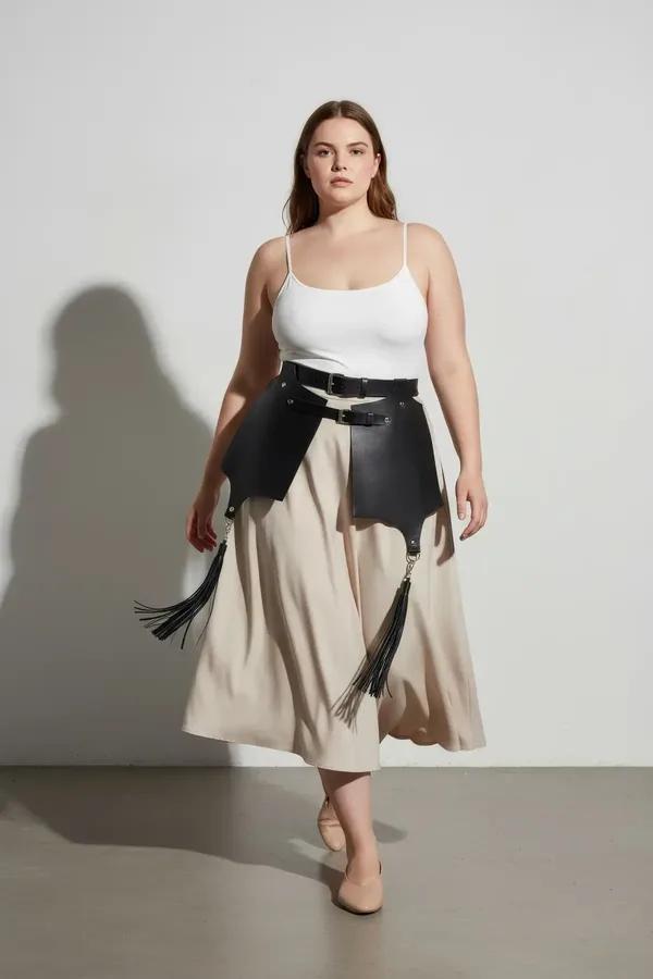 black faux leather waist harness with wide skirt panels and tassel fringe worn over white T-shirt and jeans