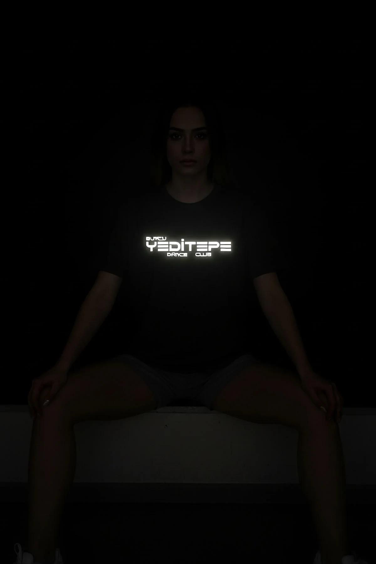 black reflective graphic t-shirt with glowing Yeditepe Dance Club chest print photographed in low light