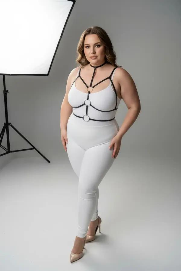 Black faux leather strappy chest harness with double gold O-rings and choker neck strap worn over white outfit