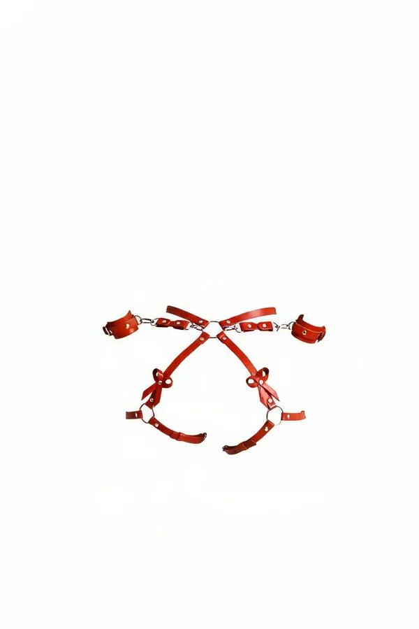 red faux leather body harness with silver O-rings and detachable wrist cuffs laid flat on white background