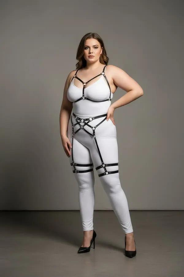 Black faux leather full body harness with chest V-frame, waist cage, and dual thigh garter bands on plus-size model
