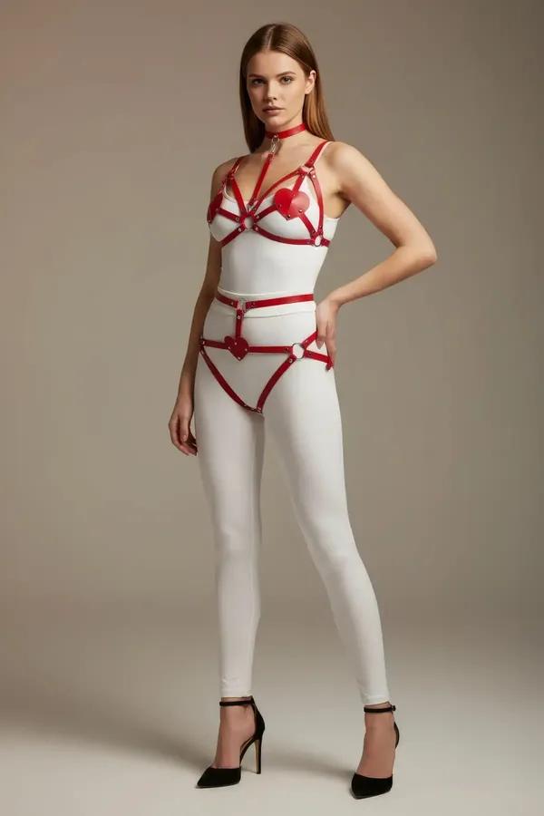 red vegan leather harness set with heart-shaped accents chest straps hip piece and matching choker worn over white bodysuit