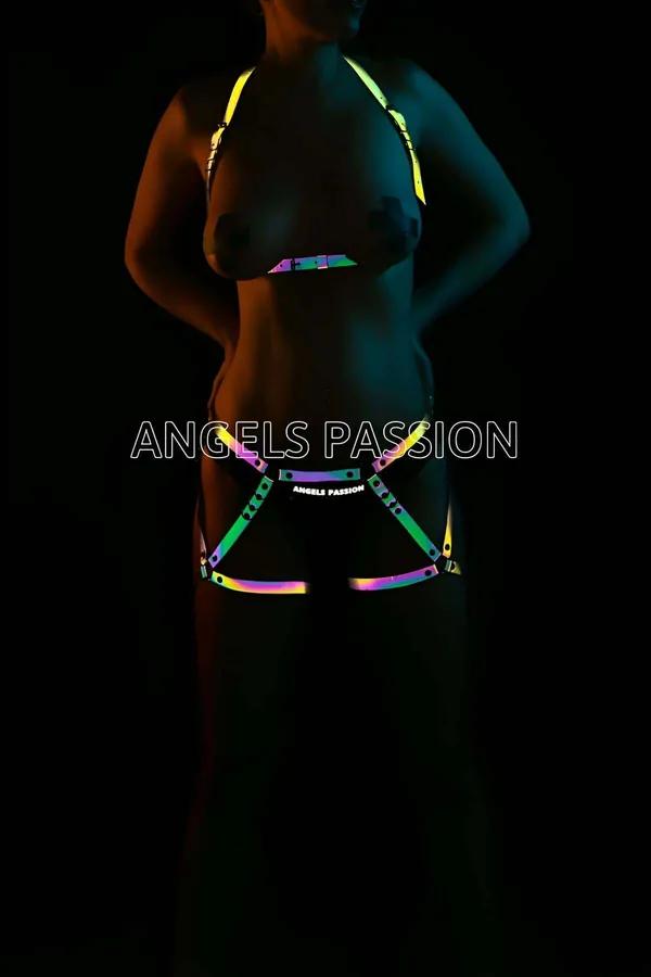 Model wearing black Iridescent Rainbow Reflective Body Harness Set glowing in a multi-colored neon spectrum under direct camera flash front view