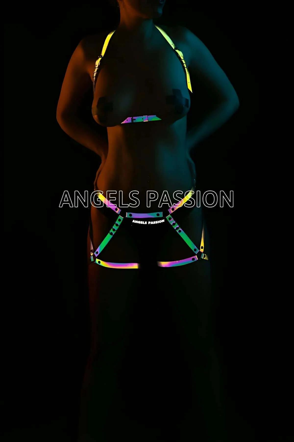 Model wearing black Iridescent Rainbow Reflective Body Harness Set glowing in a multi-colored neon spectrum under direct camera flash front view