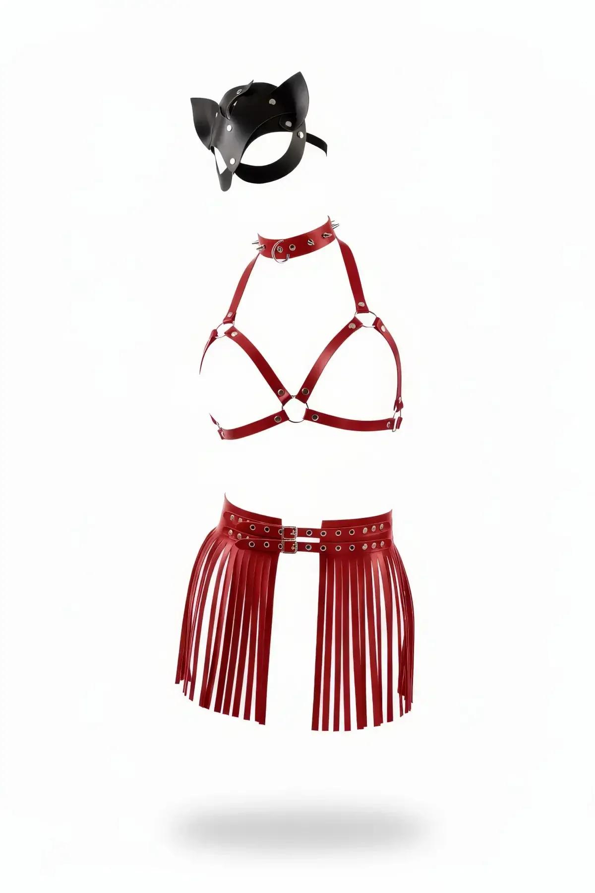 Three-piece red vegan leather harness set including a fringe waist belt, caged bra, spiked choker, and black cat mask flat lay.