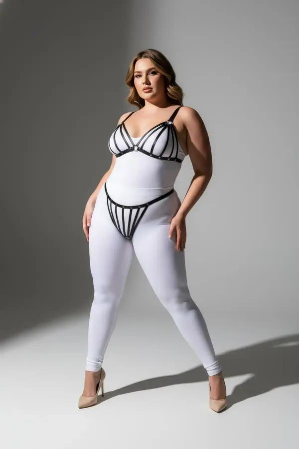 black faux leather strappy cage harness bra and thong set with silver stud hardware on plus-size model