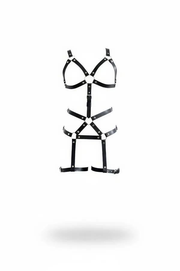 black faux leather full body harness with triangular chest cage, crossed hip panel, and silver-ring garter straps on white ba