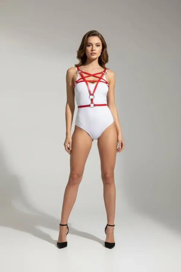 red faux leather cross-strap body harness with silver O-ring details at chest and waist, worn over white bodysuit