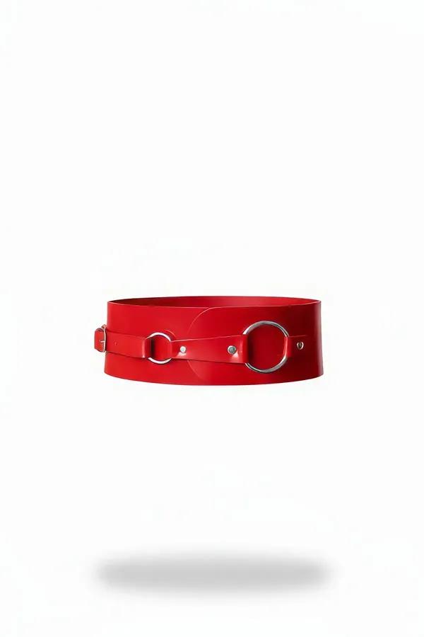 red faux leather wide waist harness with two silver O-rings and pin buckle closure on white background