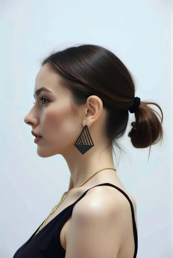 Black geometric diamond-form laser-cut matte earrings, silver stud, side profile view on woman's ear