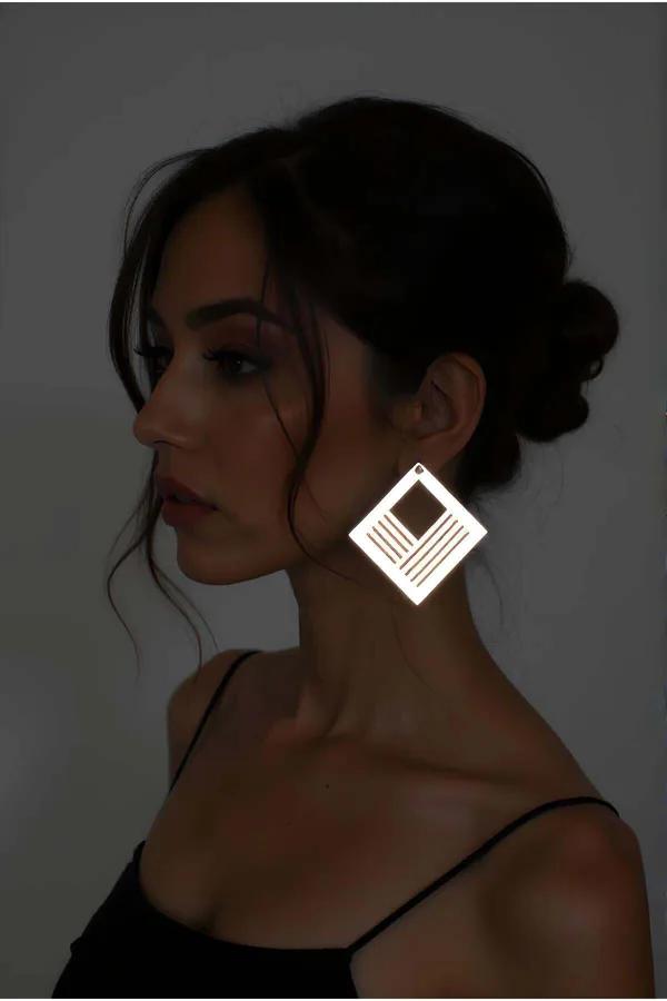 Gold mirror-finish geometric square drop earrings with parallel cutout lines and solid center worn as statement jewelry
