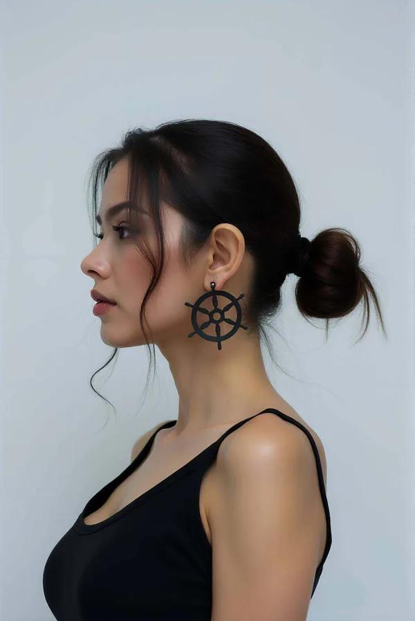 Matte black laser-cut rudder wheel drop earring profile view showing 5.5 cm circular spoke pendant against neck