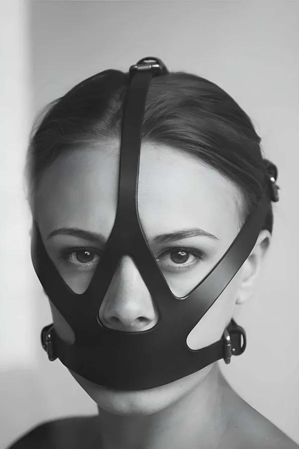 Black faux leather face mask harness with geometric strap cutouts and silver O-ring closures worn front-facing