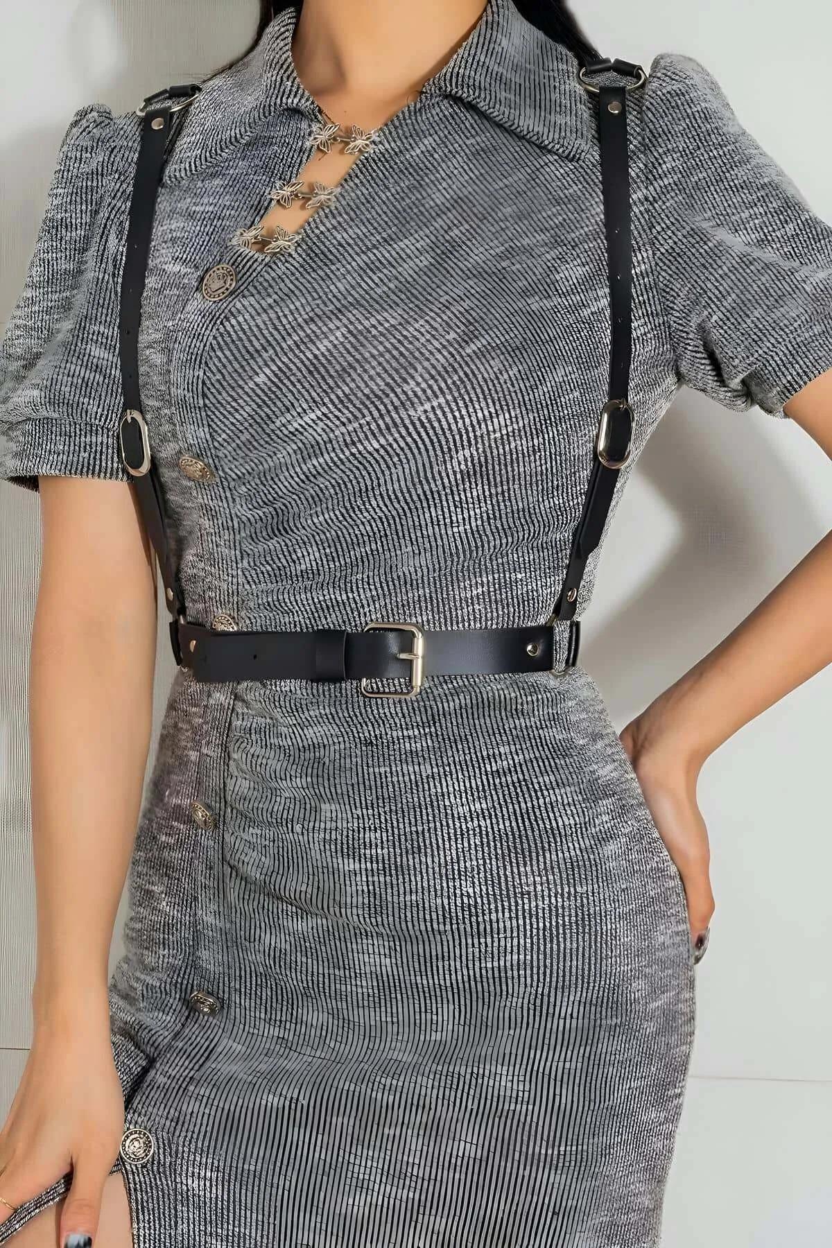 black faux leather adjustable body harness belt with silver O-rings worn over gray tweed dress