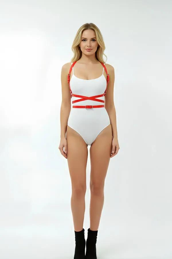 Red vegan leather cross-band body harness with X-pattern waist straps and gold buckles worn over white bodysuit