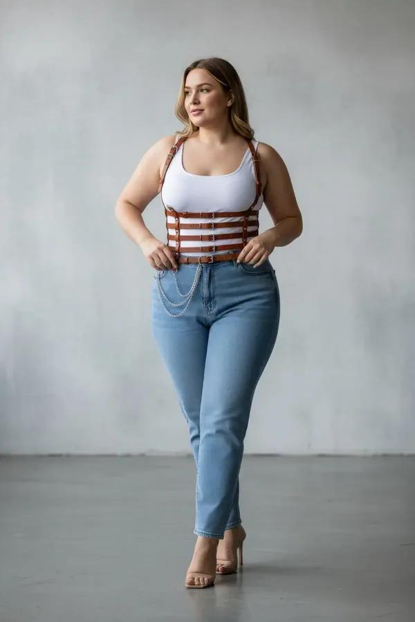 tan faux leather corset body harness with four horizontal buckle bands and draped silver chain worn over white tank top