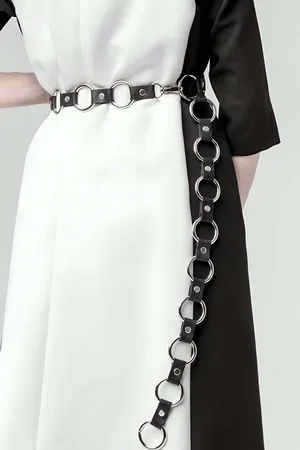 Black Faux Leather O-Ring Waist Chain Belt, featuring a long draping silver O-ring chain, worn over a white dress