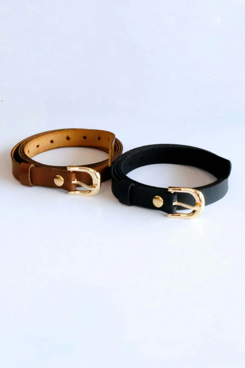 Black and tan faux leather belts with buckles laid out on a white background.