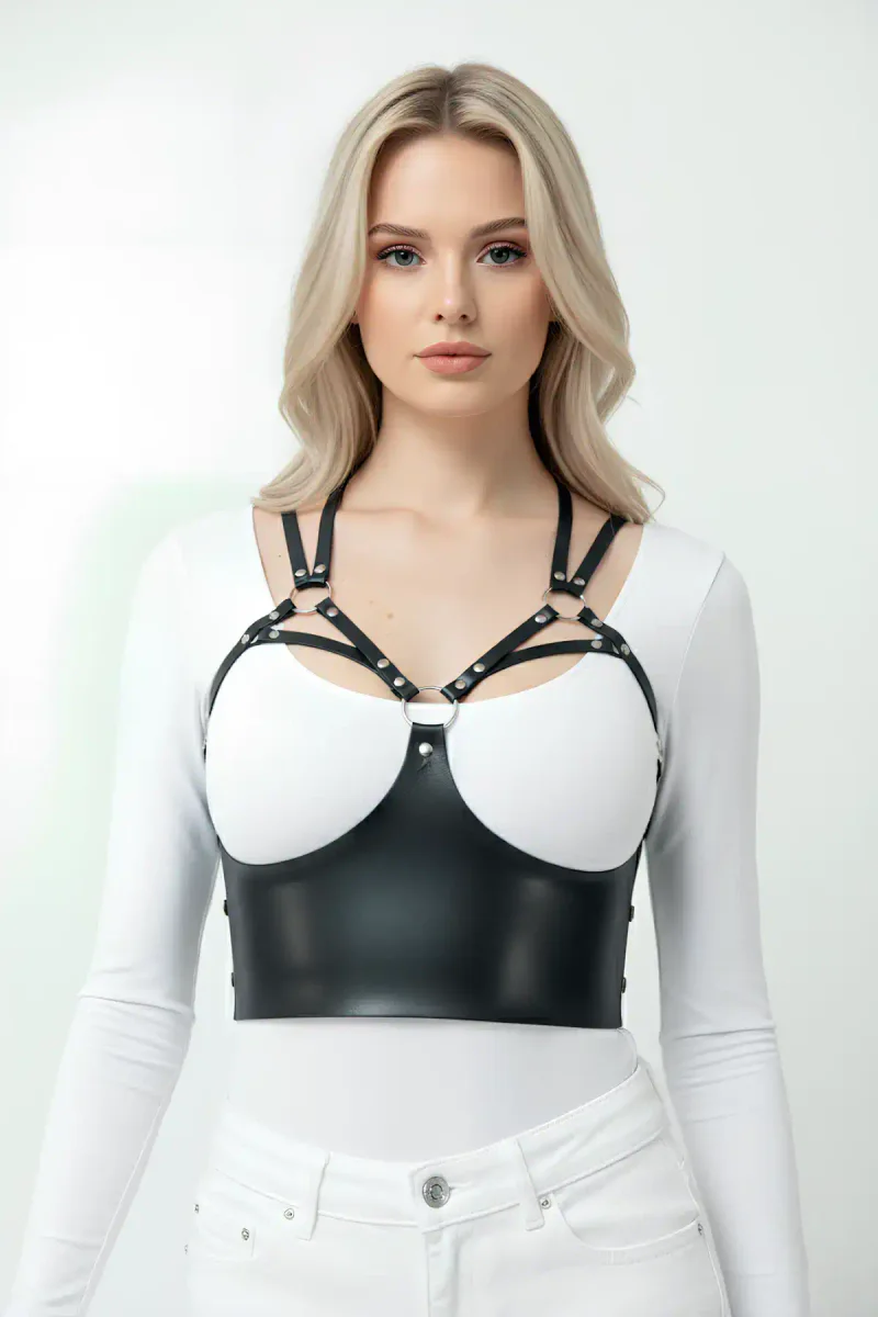 Black faux leather O-ring body harness shown over white bra and jeans